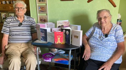 June and Bill Franks celebrate their 70th wedding anniversary sat either side of a desk with anniversary cards between them