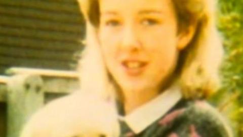 Diane Sindall, who has blonde hair, smiles at the camera while holding a light coloured puppy which appears to be a labrador