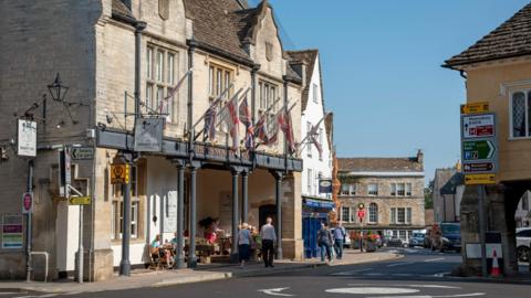 Entrance to pub and shops with people walking past