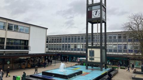 A view of Stevenage town centre showing the clock tower and water feature surrounded by shops