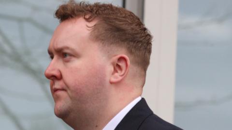 A man in a dark suit arriving at court