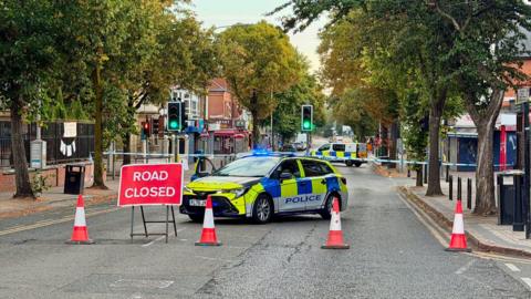 A cordon in place with a road closed sign
