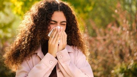 A woman in discomfort presses a tissue to her nose