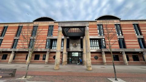 A three-storey red brick court building with two stone columns either side of the front door.
