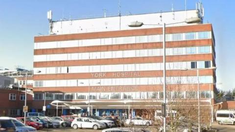 The outside of the building of York Hospital, with cars parked outside.