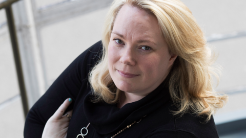 Blonde woman with her arms folded looking up at the camera