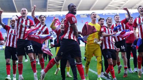Lincoln players celebrate on the pitch at Reading's Select Car Leasing Stadium