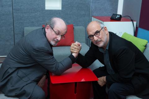 Salman Rushdie and Alan Yentob look at the camera as they arm wrestle