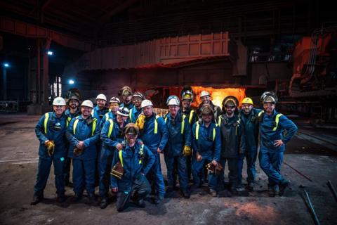 Tata Steel workers in their uniforms in front of heavy machinery on the final day of traditional steelmaking in Port Talbot