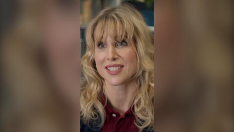 Amanda looks straight at the camera and smiles. She wears a burgundy polo shirt.