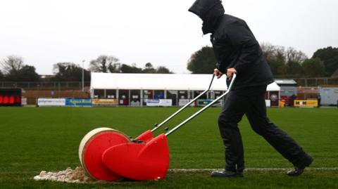 Ground staff mop up the Truro City pitch