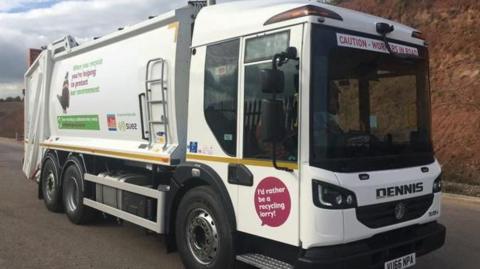 Parked recycling lorry. The vehicle is white with the East Devon District Council and Suez logo.