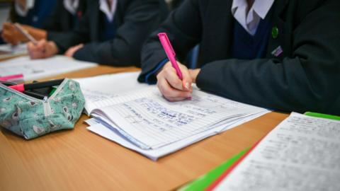 Pupils writing at a desk