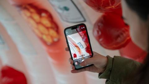 Someone taking a picture on their phone of the interactive display