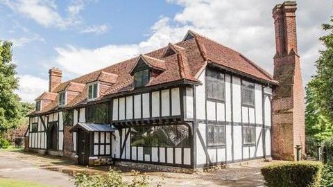 A medieval house. It is a white building with black stripes on it. 