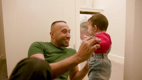 A father and son play by the washing machine.