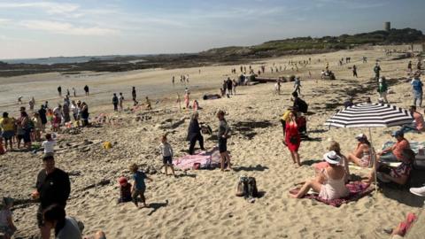 People on the beach in Guernsey on a sunny and partly cloudy day