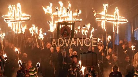 People parade through the streets with blazing torches