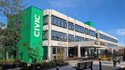 The former civic centre in Wigan town centre, a four-storey building with windows on each floor divided by long strips of concrete, and imposing entranceways. 