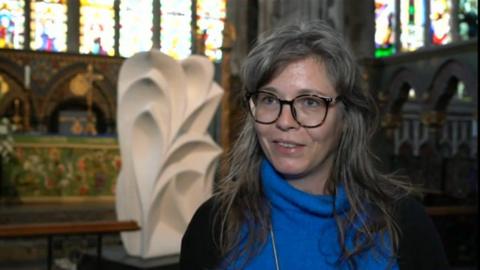 Jess Richards standing in a church in front of a white sculpture