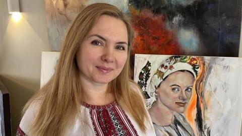 Viktoriya Richardson from Canterbury wearing Ukrainian national dress in her living room surrounded by her works of art