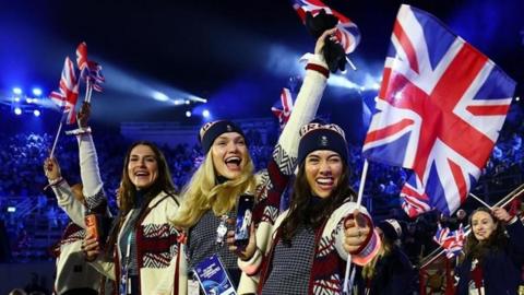 Women wave the Union Jack and smile at the Winter Olympics closing ceremony