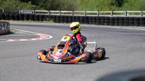 Noah drives his kart round the bend of a race track.