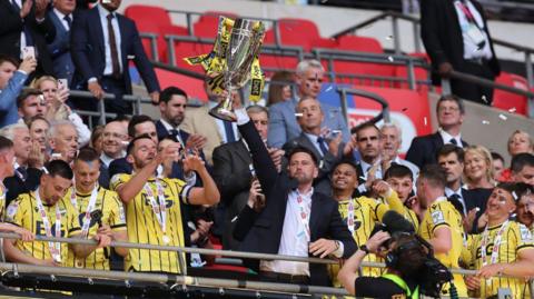 Oxford boss Des Buckingham holds the play-off final trophy