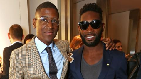 The DJ Labrinth stands with his arm around fellow DJ Tinie Tempah. They both smile at the camera.