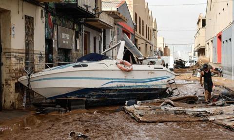 A boat washed up a muddy street following floods in Valencia