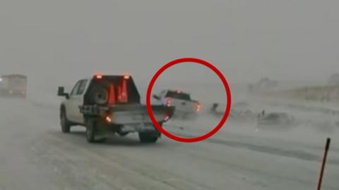 A vehicle circled in red nearly collides with a person on the side of a white snow-covered road as another service truck drives nearby in the foreground.