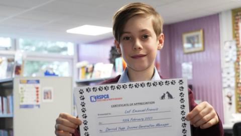 A young boy holds up a special certificate in recognition of his fundraising efforts for the RSPCA