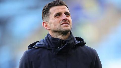 John Mousinho looking to the sky ahead of a Portsmouth game