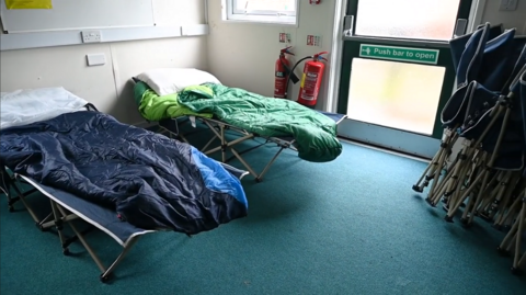 Two camping beds with sleeping bags and a pillow on top. 