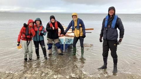 A group of people stand around a boat