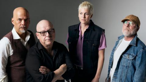 The 2024 line-up of Pixies pose against a grey-silver backdrop