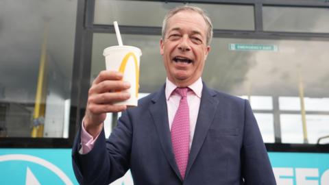 Nigel Farage holding a McDonalds milkshake in his right hand