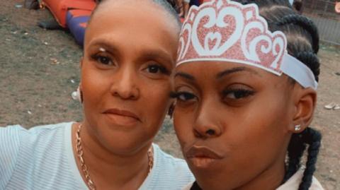 Fiona Holm, a black woman of 48 with her hair tied back, with her daughter Savannah Holm-Aderemi, a young black woman with long braided hair