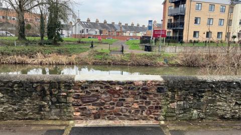 The section along the River Tone where the footbridge used to be. A gap in the wall has been filled in.