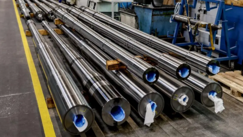 A large pile of thick metal tubes stacked on wooden racks
