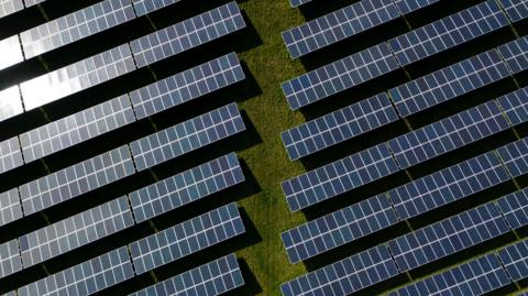 An aerial view shows rows of black photovoltaic (PV) solar panels.