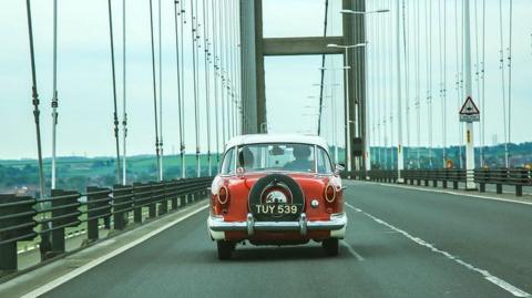 A vintage red car travelling across the Humber Bridge 