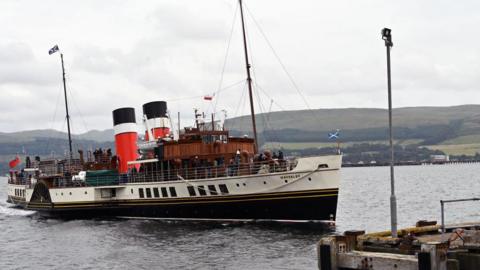 the paddle steamer in the water as it approaches a pier