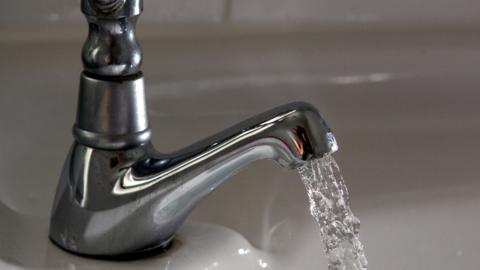 A tap with water running out of it into a sink. 
