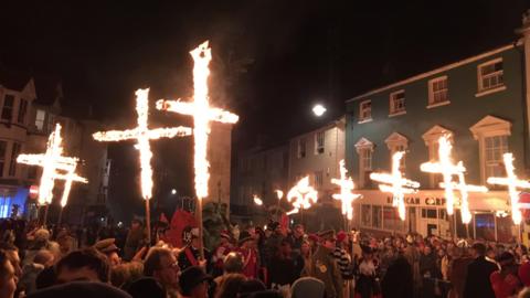 Burning crosses being carried through the streets of Lewes, as a large crowd of people watch.