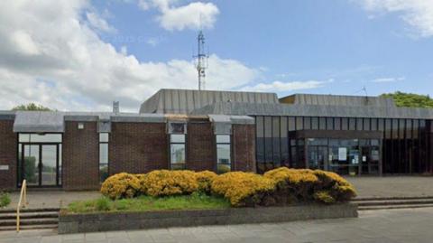 Court building in Fleetwood with 1970s style architecture featuring brick and glass frontages with bushes in front. 