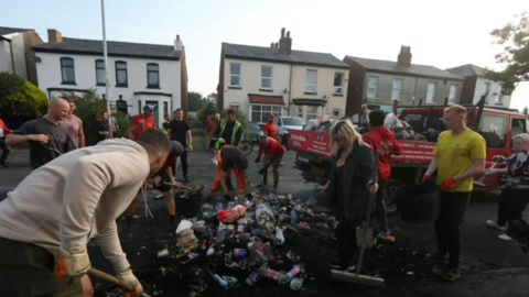 In the aftermath of the rioting in Southport, volunteers come out to help rebuild walls that were demolished by the rampaging mobs. They collect up rubble, empty beer cans and other litter. 