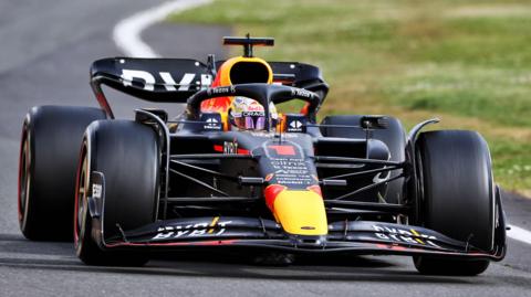 A black F1 car driving on a track.  