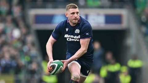 Finn Russell runs and holds the ball in two hands to his right hand side ready to pass the ball during Scotland's Six Nations match against Ireland