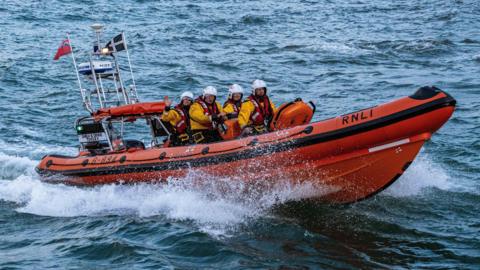 An Atlantic 85 class lifeboat at sea with a crew of four aboard. It is a rigid inflatable boat.